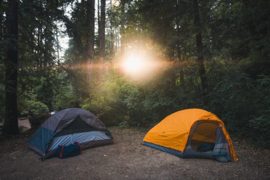 A photo of two tents with the sun shining.