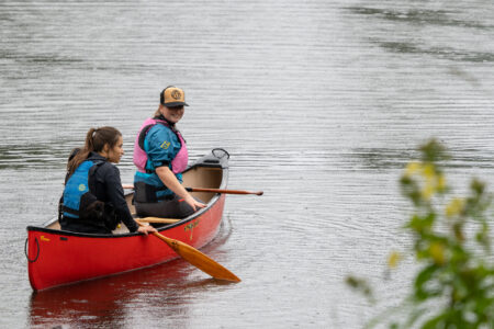 Two ladies canoeing in the rain.