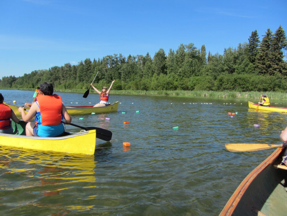 Kids paddling a canoe as part of a waterfront canoe course.